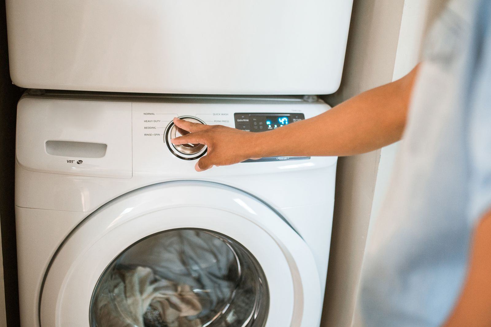 A person loading laundry into a front-load washing machine