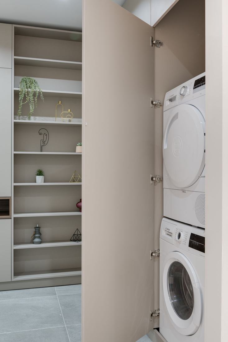 A stacked washer and dryer built into a tight cabinet closet