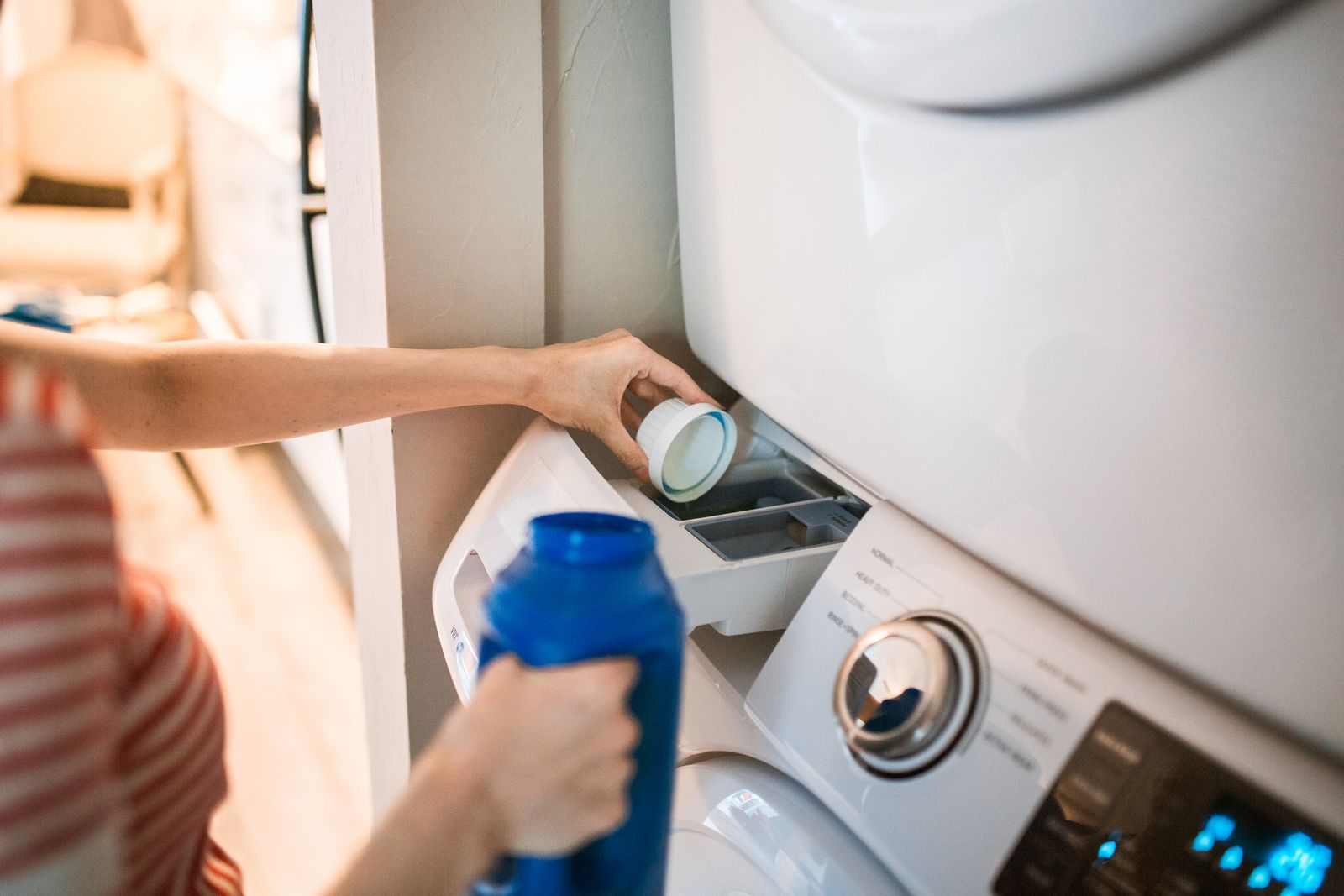 A stacked compact washer and dryer installed in a narrow apartment laundry closet